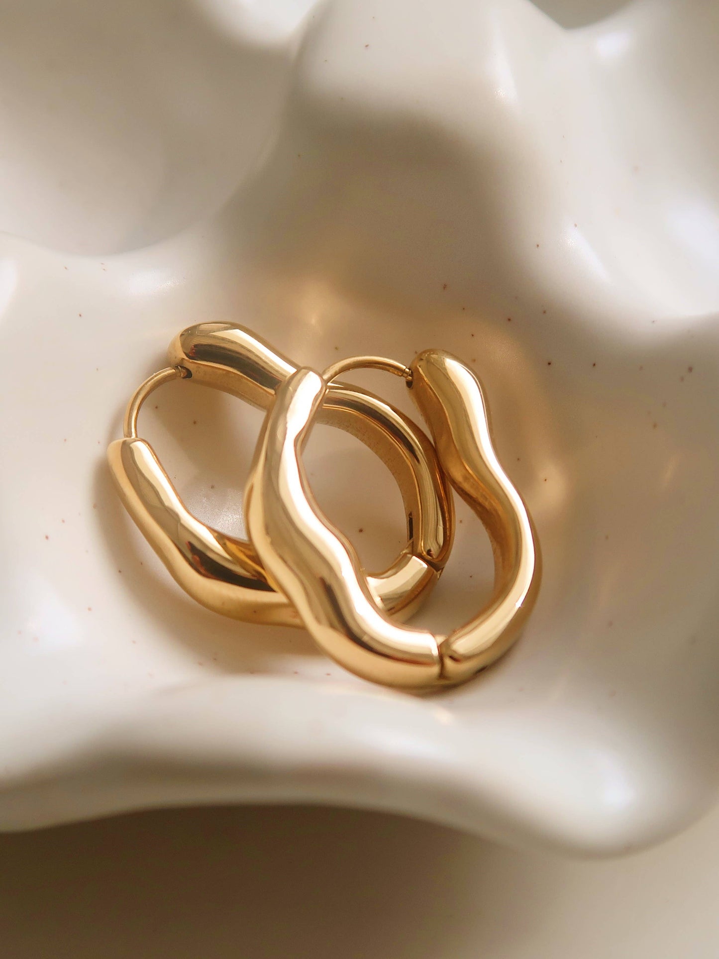 Darcy 18K gold non-tarnish oval hoop earring by Flanerie, showcasing a sleek, polished gold finish and oval shape.