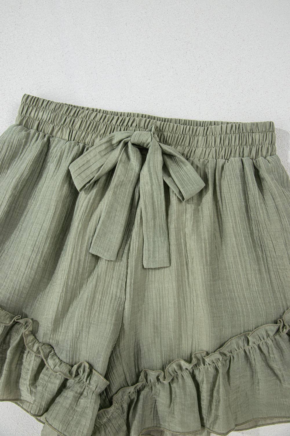 Laurel green textured tie waist shorts with ruffle hem by Lovesoft, showcasing the stylish design and fabric detail.