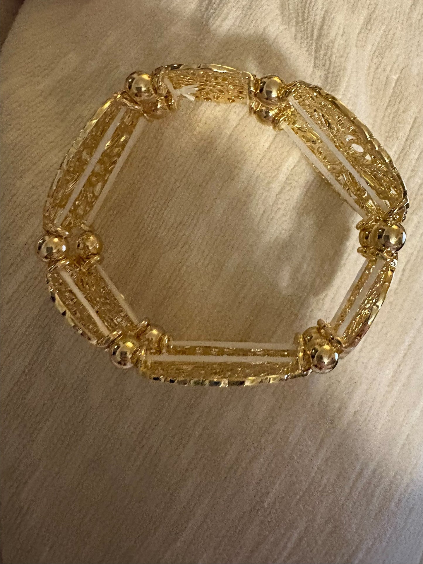 Gold filigree stretch bangle bracelet by S&A Fashions with intricate openwork design on smooth, flexible band.
