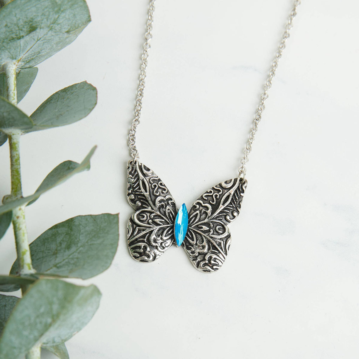 Antique silver butterfly pendant necklace with engraved details on an 18-inch chain, featuring a Howard's Zenni design.