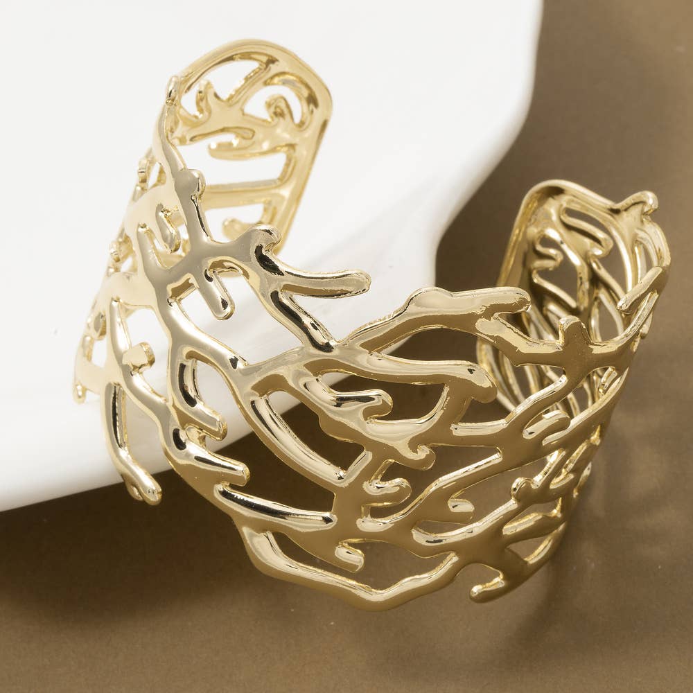 Gold bracelet with intricate design on a white surface