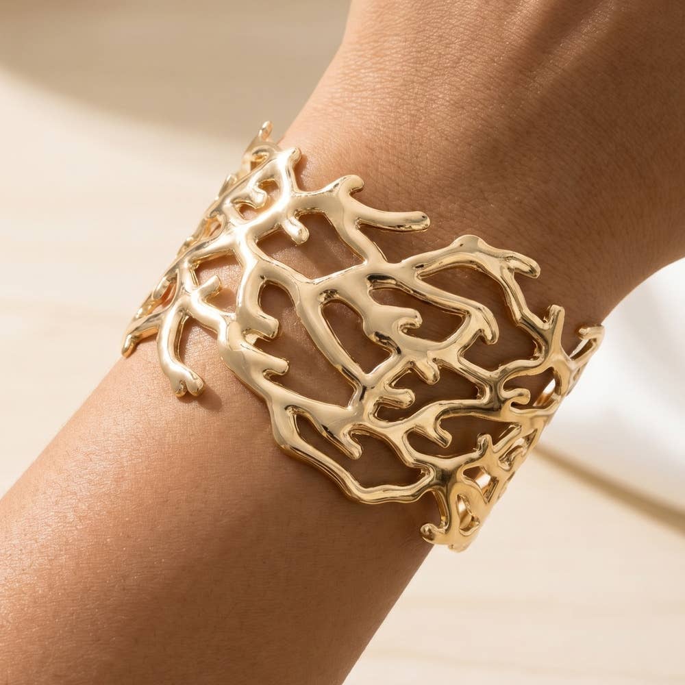Gold leaf bracelet on a wrist with a neutral background