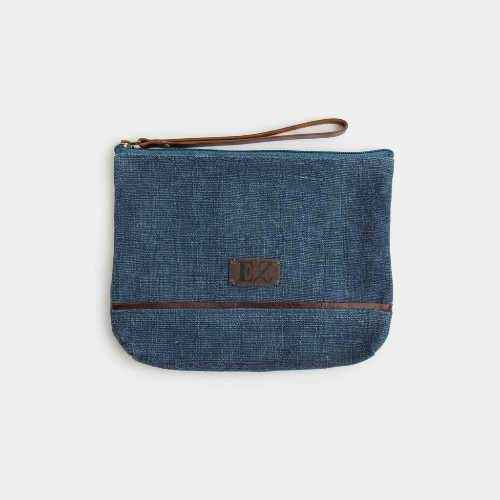 Blue denim pouch with brown zipper and strap on a white background