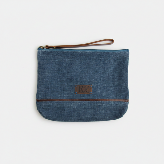 Blue denim pouch with brown zipper and strap on a white background