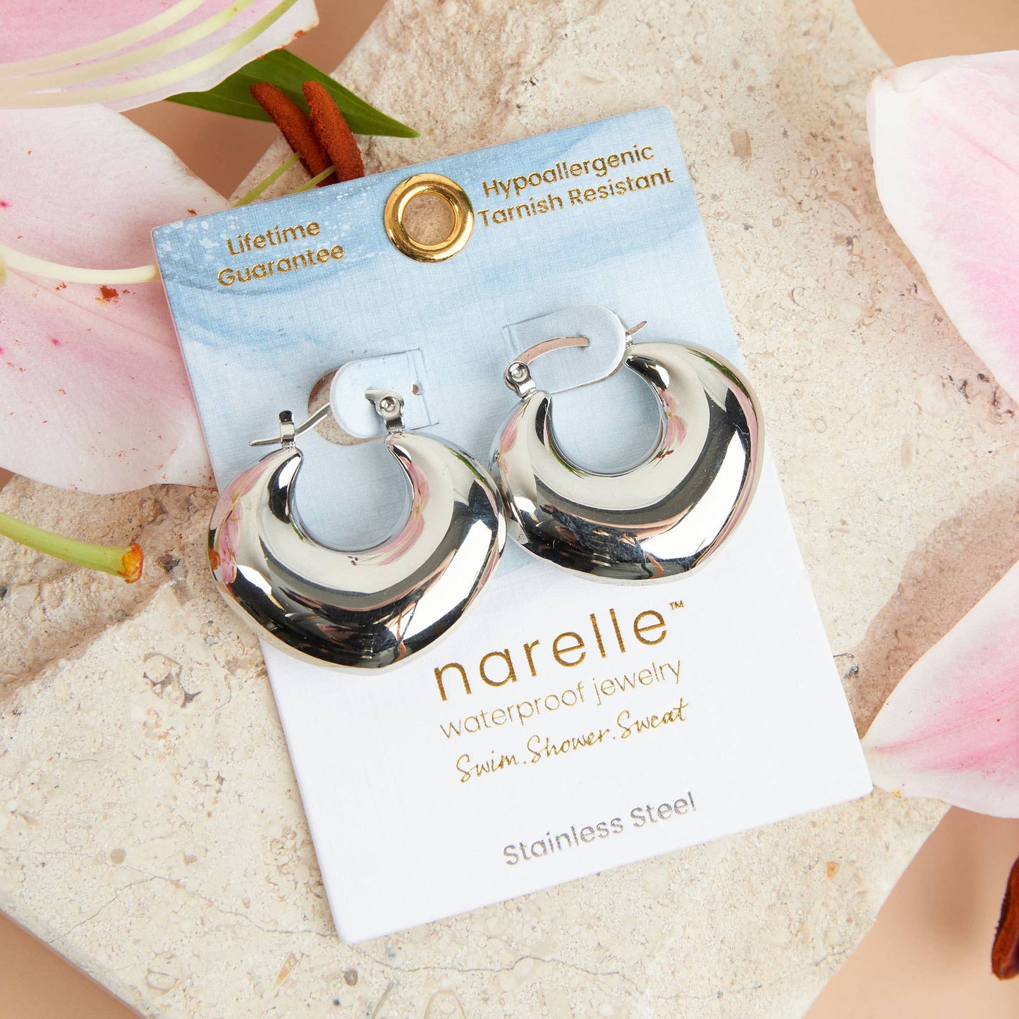 Silver hoop earrings on a Narelle jewelry card with floral background