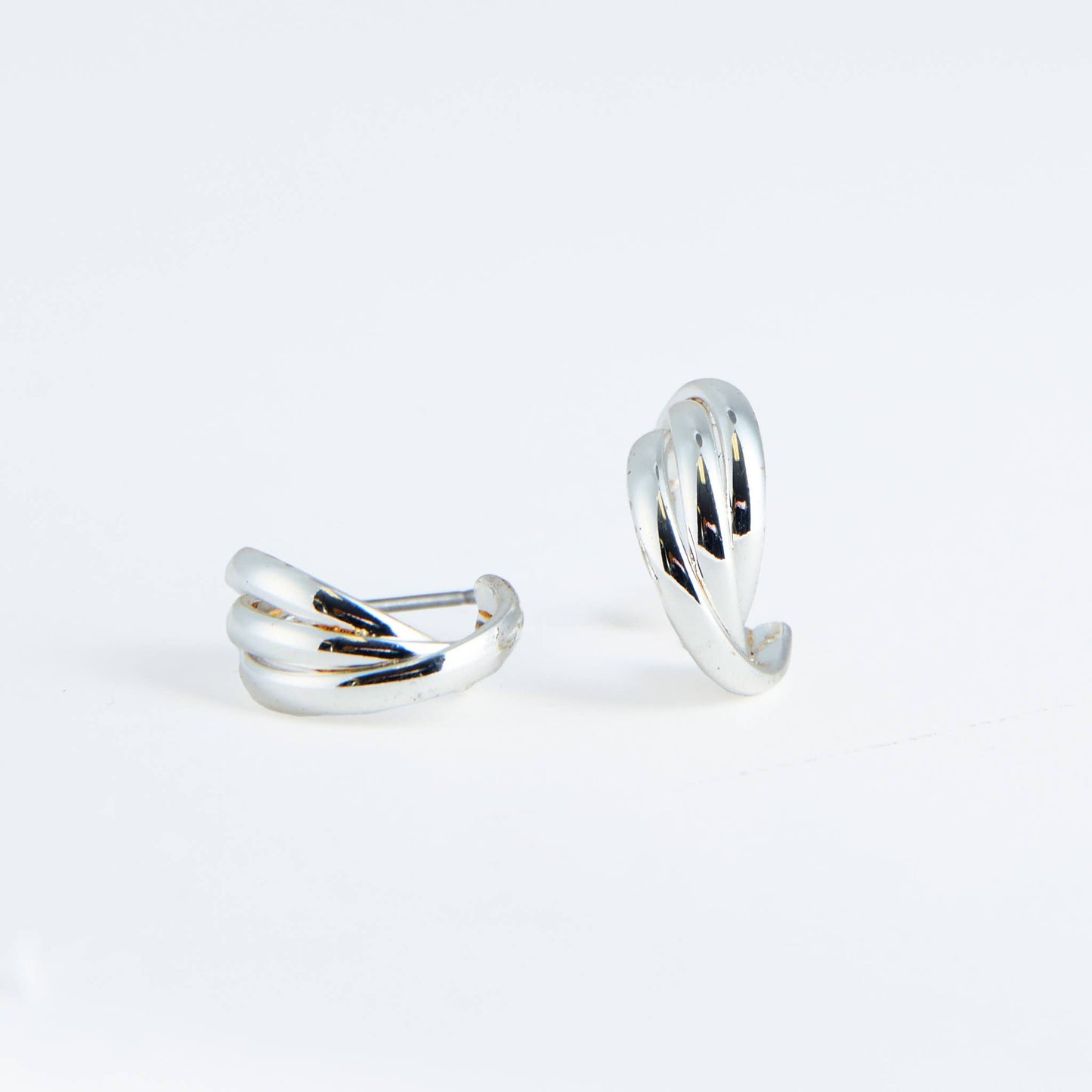 Two silver hoop earrings on a light gray background