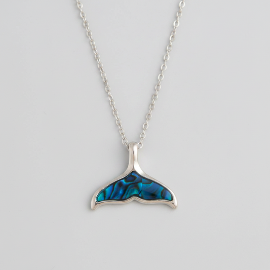 Silver necklace with a blue whale tail pendant on a light gray background
