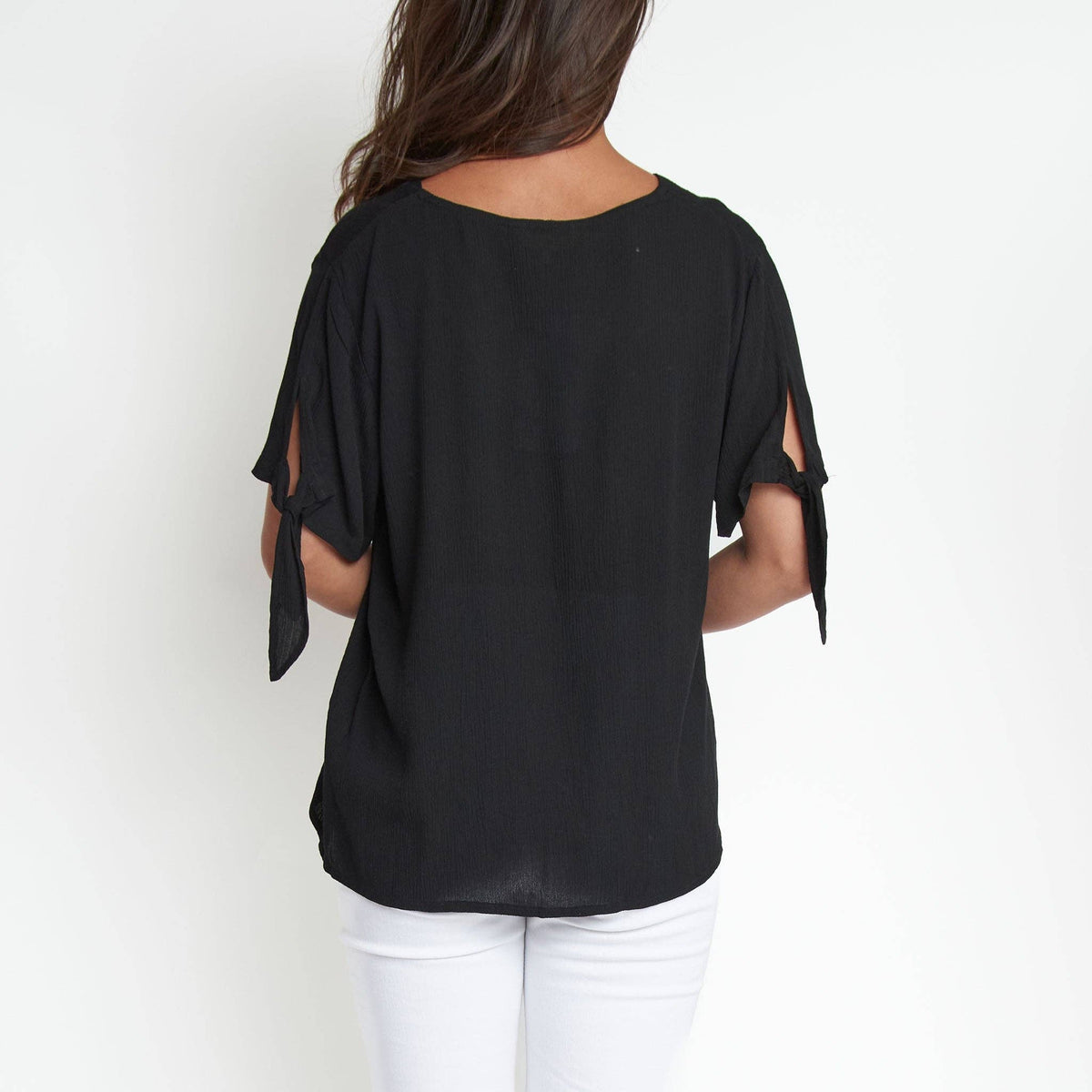 Elsie & Zoey Nika crepe tied short sleeve V-neck blouse hanging on a hanger, showing front view with tied detail and crepe fabric.