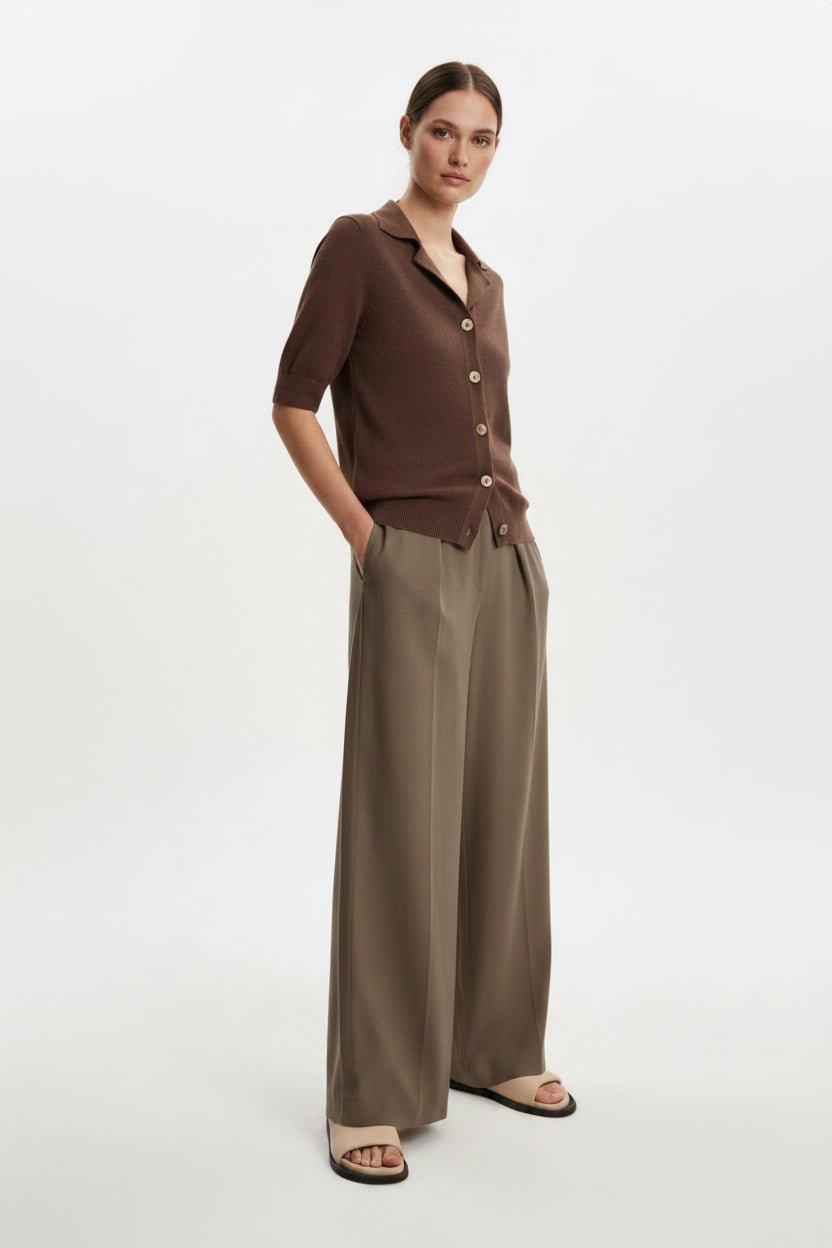 Woman wearing a brown top and beige pants on a beige background