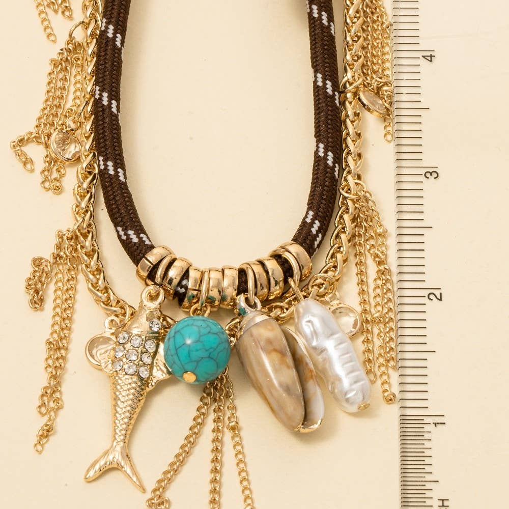 Necklace with various charms and a ruler for scale on a beige background