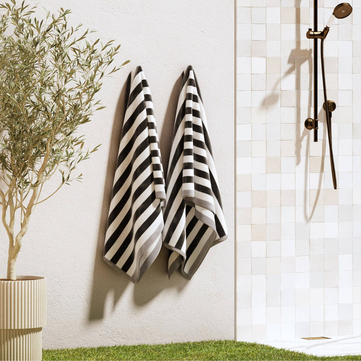 Oversized Santa Cruz striped border cabana beach towel by BH Collective laid out on sand with ocean in the background.