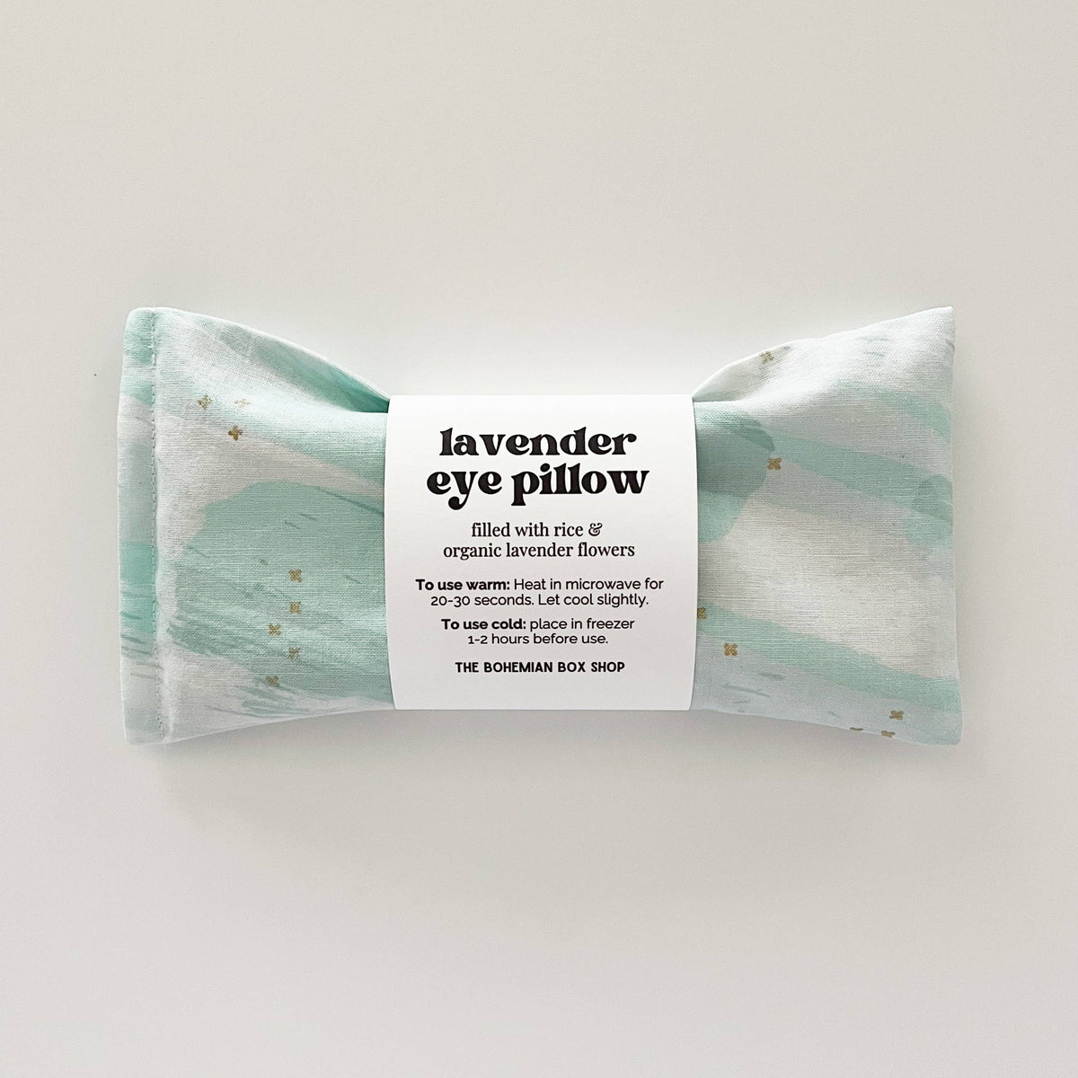 Lavender eye pillow with mint, white, and gold star patterns from Bohemian Box Shop, featuring soft fabric and decorative design.