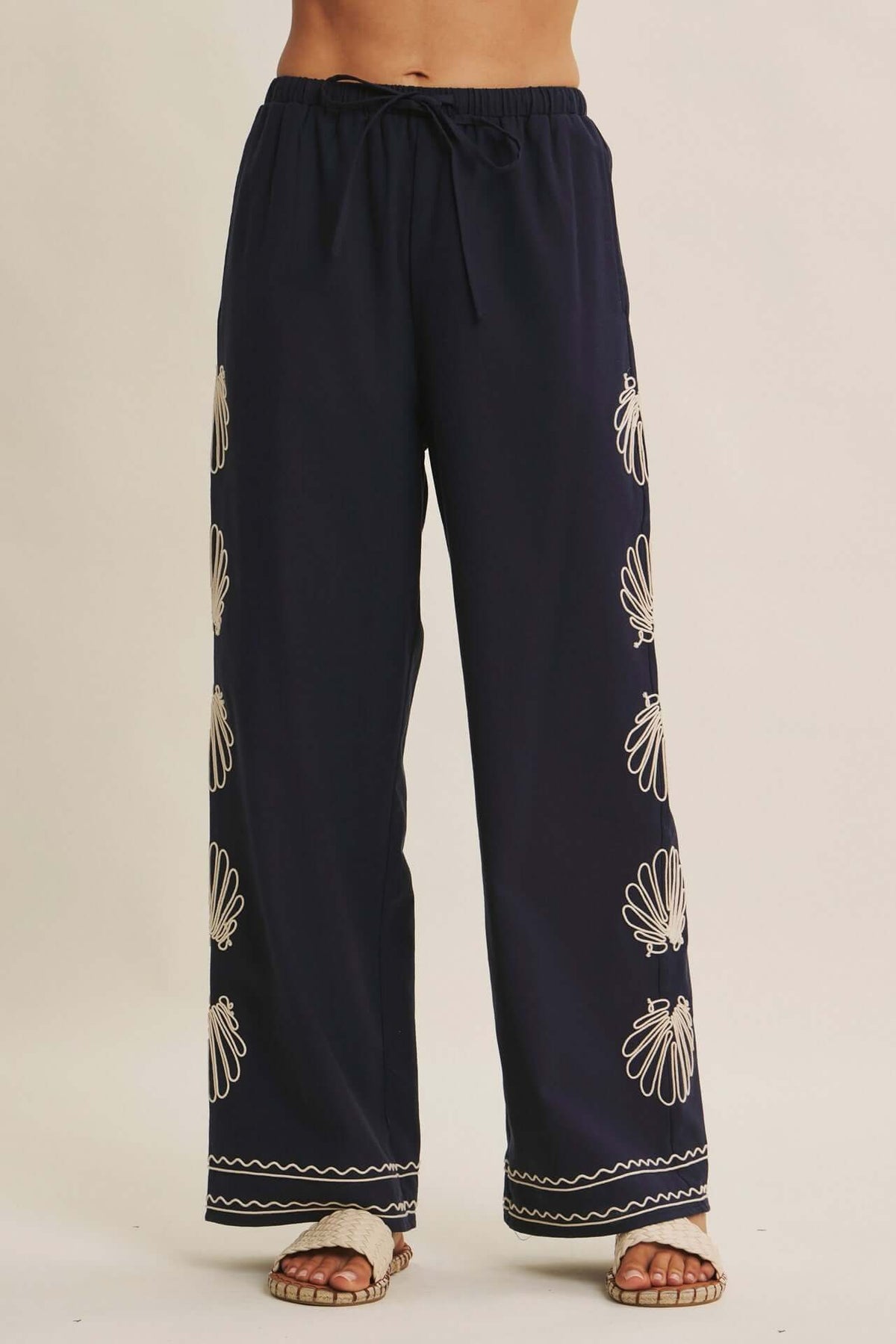 Navy seashell-embroidered wide-leg pants with drawstring waist from Chic Speak Boutique, showcasing relaxed, flowing style.