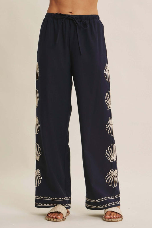 Navy seashell-embroidered wide-leg pants with drawstring waist from Chic Speak Boutique, showcasing relaxed, flowing style.