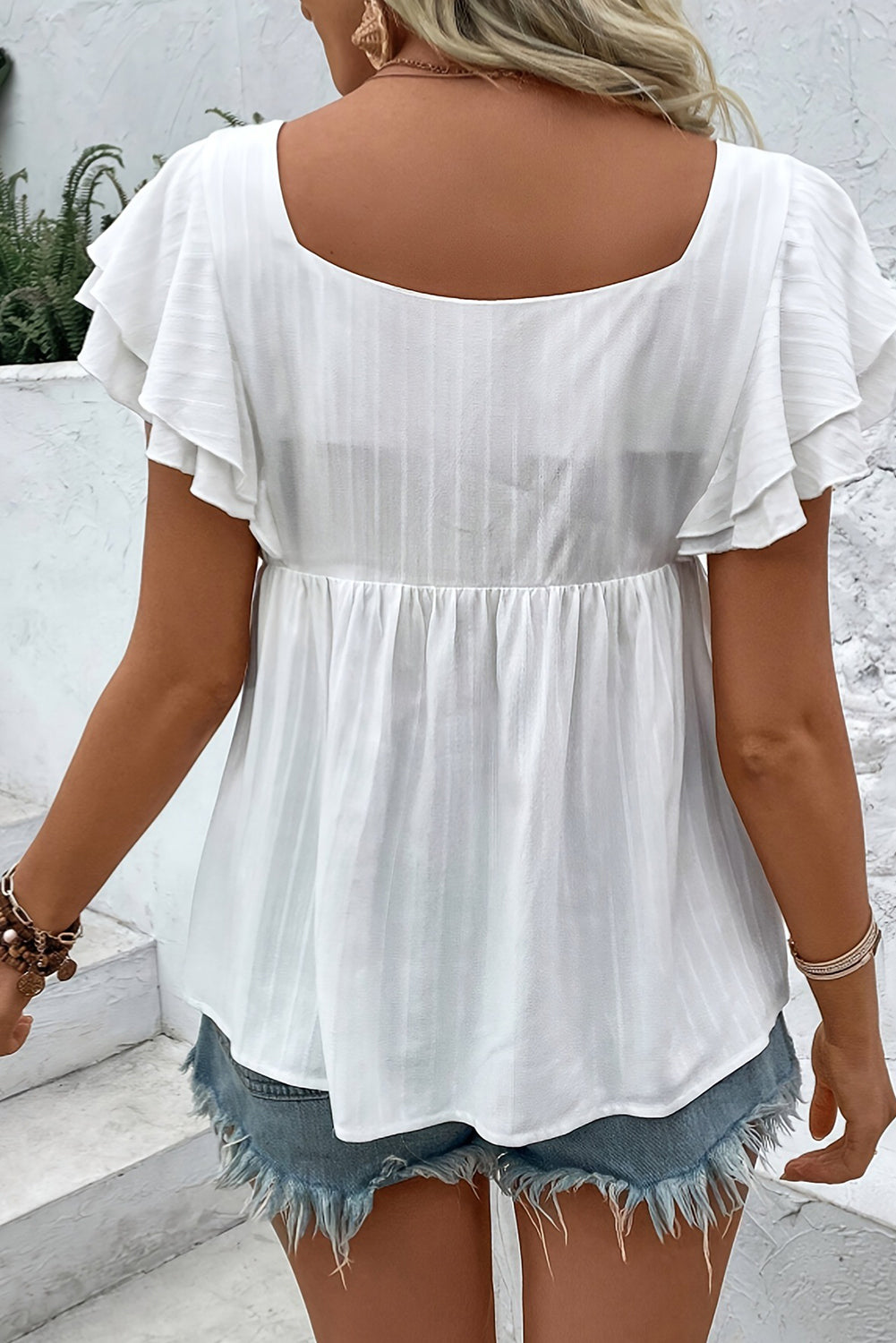 White blouse with denim flower embellishments from CSB Private Label Chic Speak Boutique, displayed on a hanger.