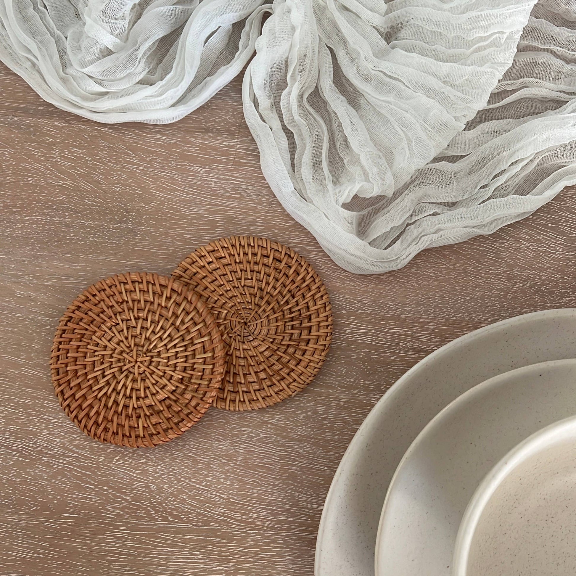 Set of natural rattan coasters by Delmar Decor, round woven coasters for protecting surfaces and adding rustic charm.
