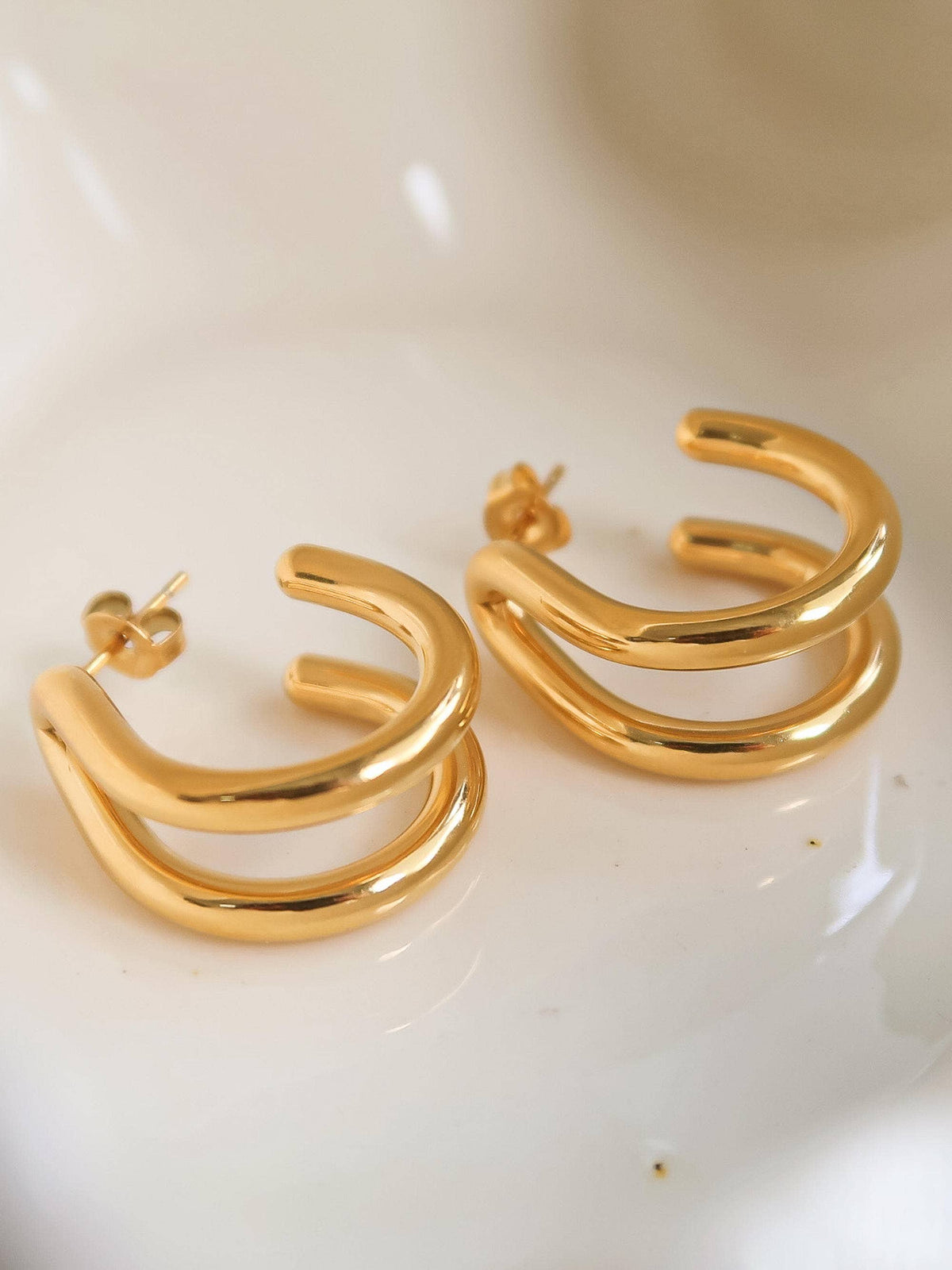 18K gold non-tarnish double C hoop earring by Flanerie by MAIQ, showing two interconnected gold hoops with a polished finish.