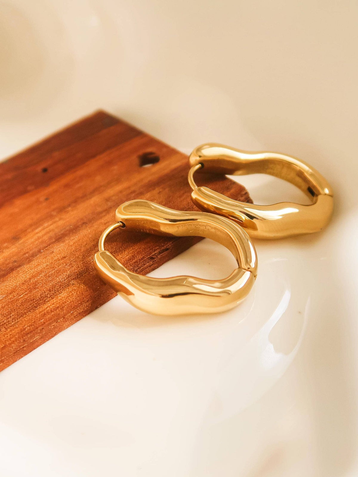 18K gold non-tarnish oval hoop earring from Flanerie by MAIQ, showcasing a sleek, polished gold hoop on a plain background.