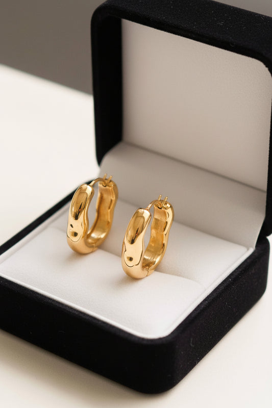 Darcy 18K gold non-tarnish oval hoop earring by Flanerie by MAIQ, close-up view showing smooth polished surface and oval shape.