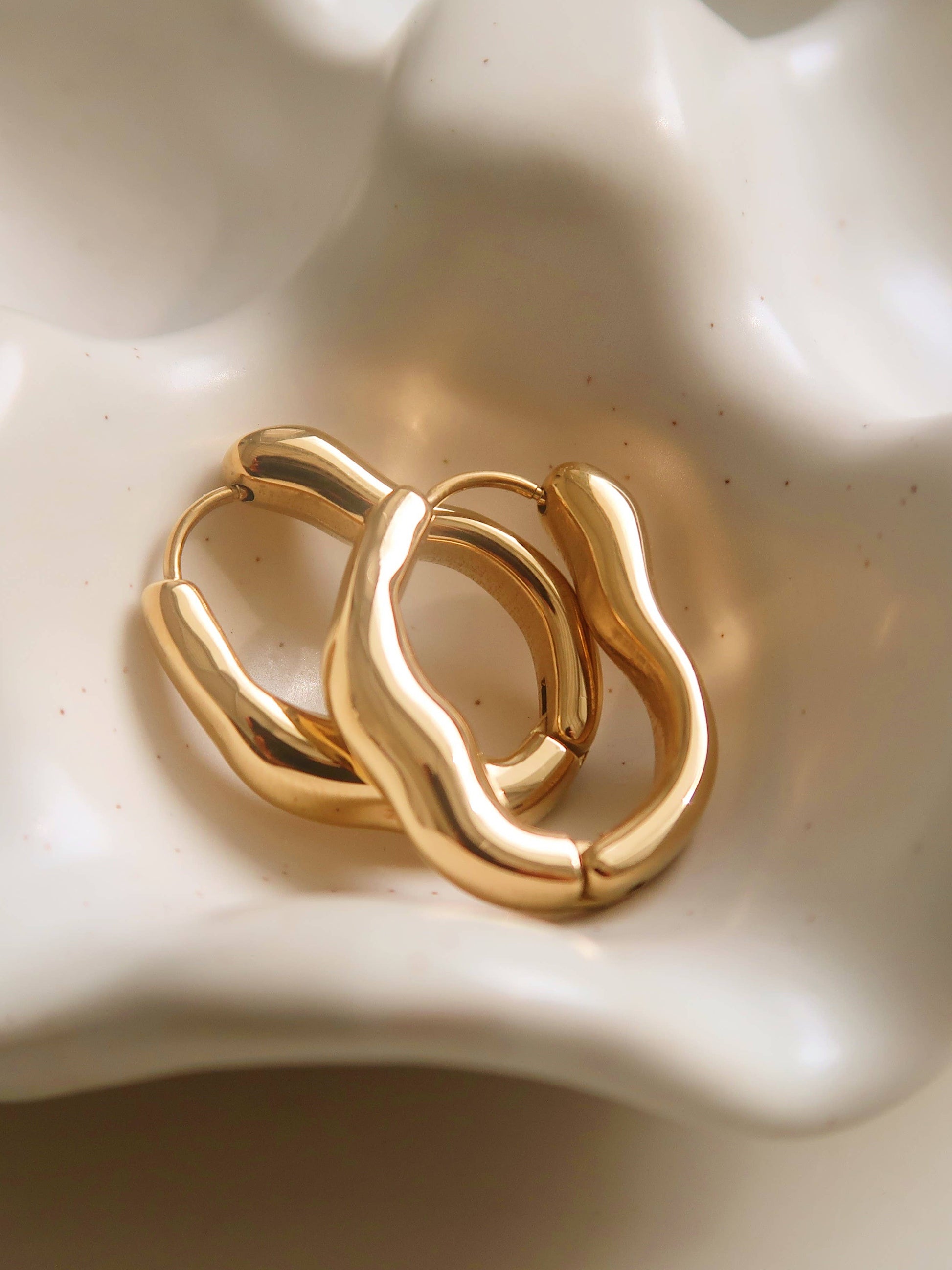 Darcy 18K gold non-tarnish oval hoop earring by Flanerie, showcasing a sleek, polished gold finish and oval shape.
