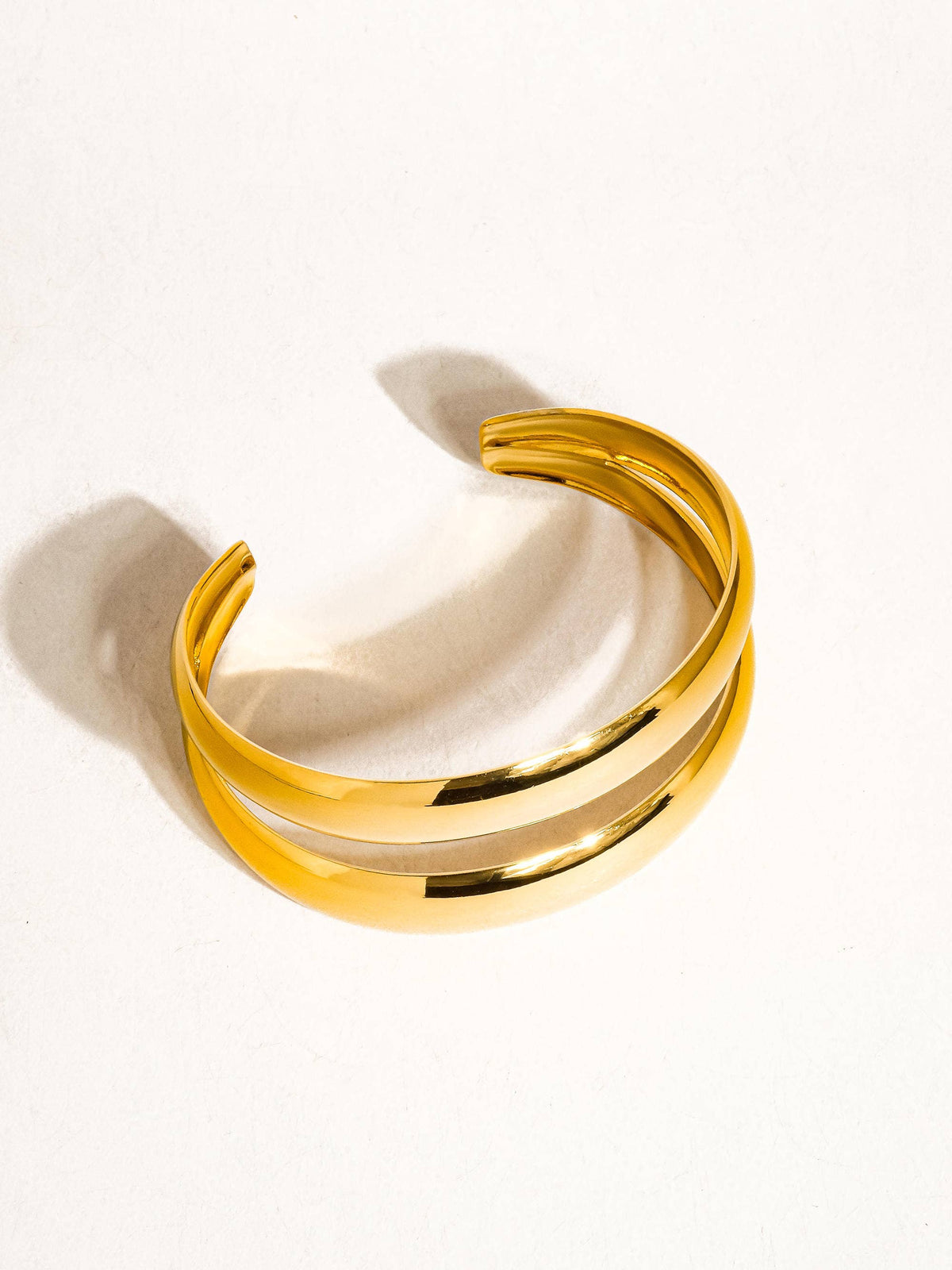 Ronan 18K gold layered round bangle by Flanerie by MAIQ, showcasing a polished, non-tarnish gold finish on a sleek, rounded design.