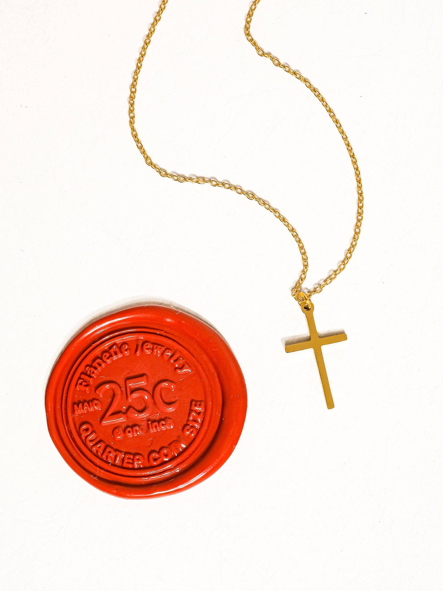 Flanerie by MAIQ Tirza 18K gold non-tarnish small cross necklace hanging on a chain, close-up view of the jewelry.