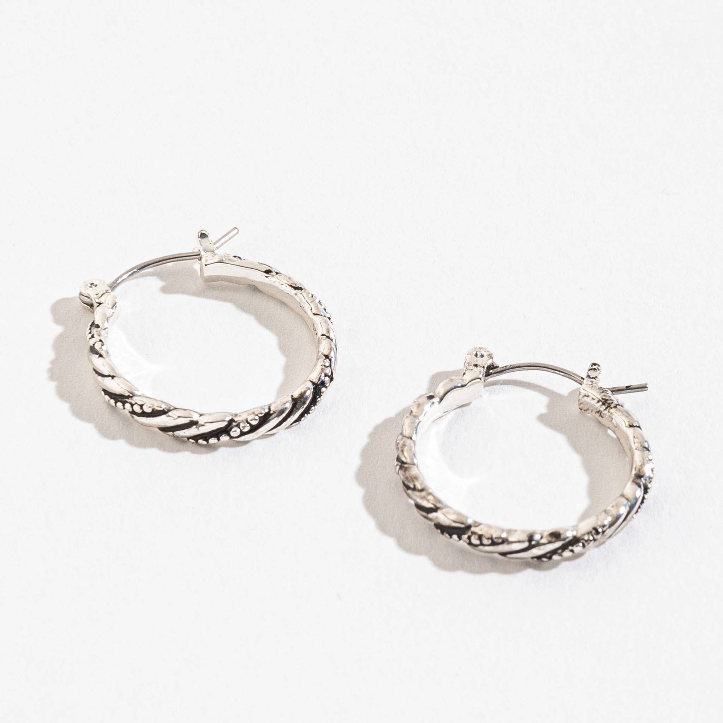 Howard's Earsense Twist Hoop Earrings, silver-tone, twisted hoop design, close-up of stylish jewelry on a white background.