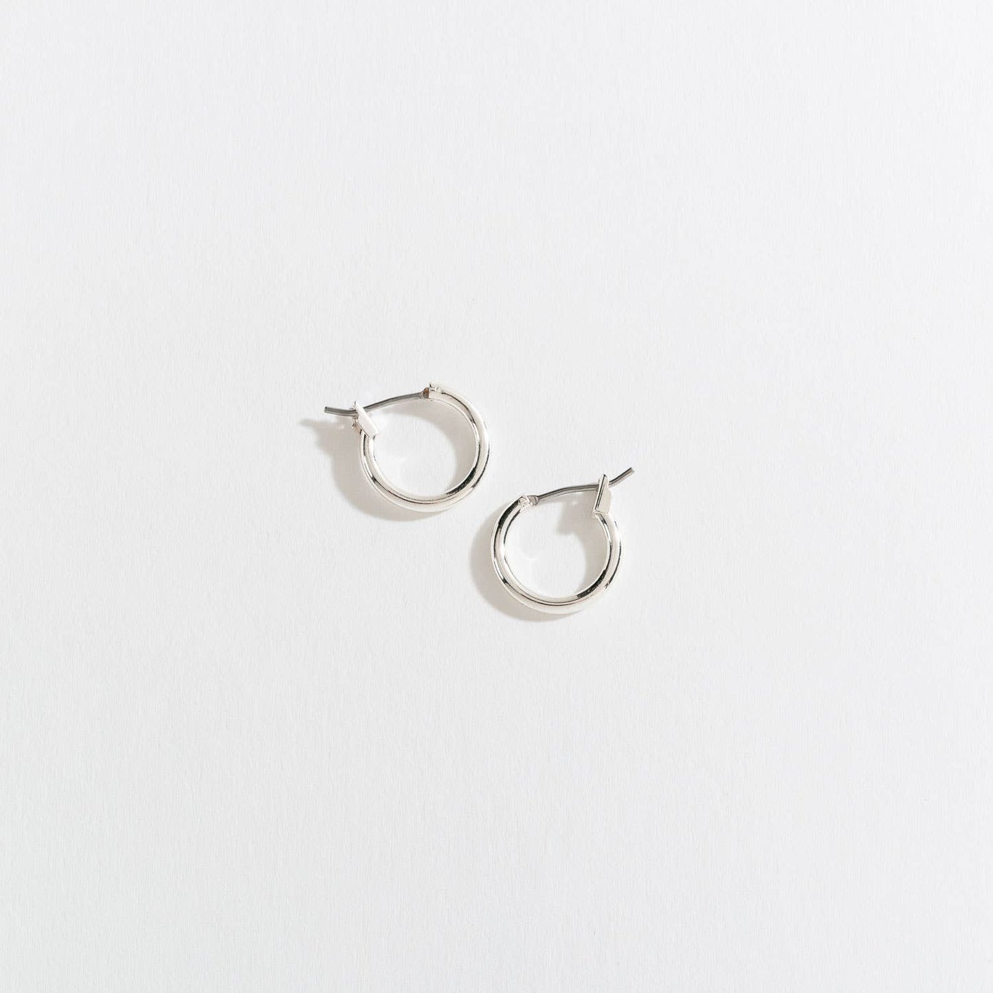 Howard's Ear Sense Click Hoop Earrings showcasing shiny silver hoops with secure click closures on a white background.