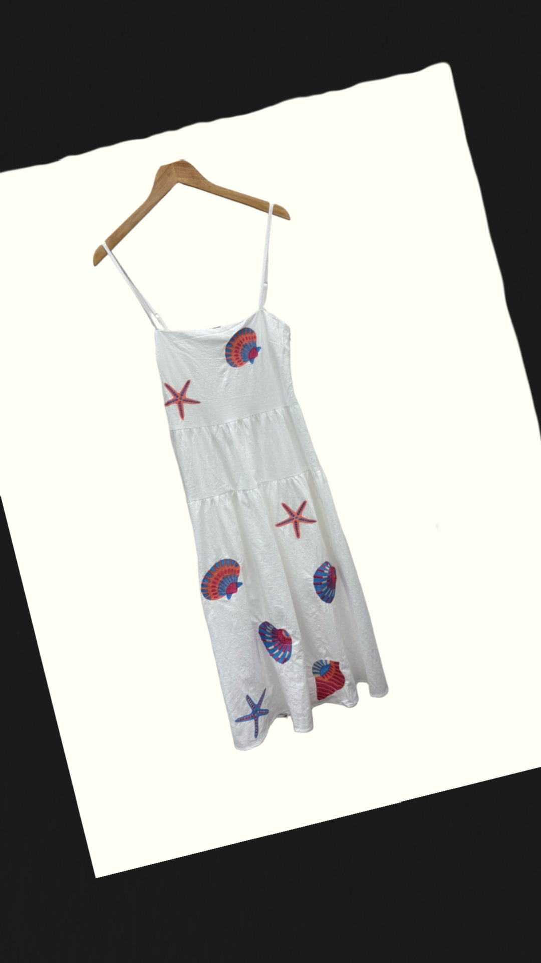 Cotton Coastal Sun Dress by Chic Speak Boutique displayed on a hanger, featuring a flowing, lightweight fabric with coastal-inspired patterns.