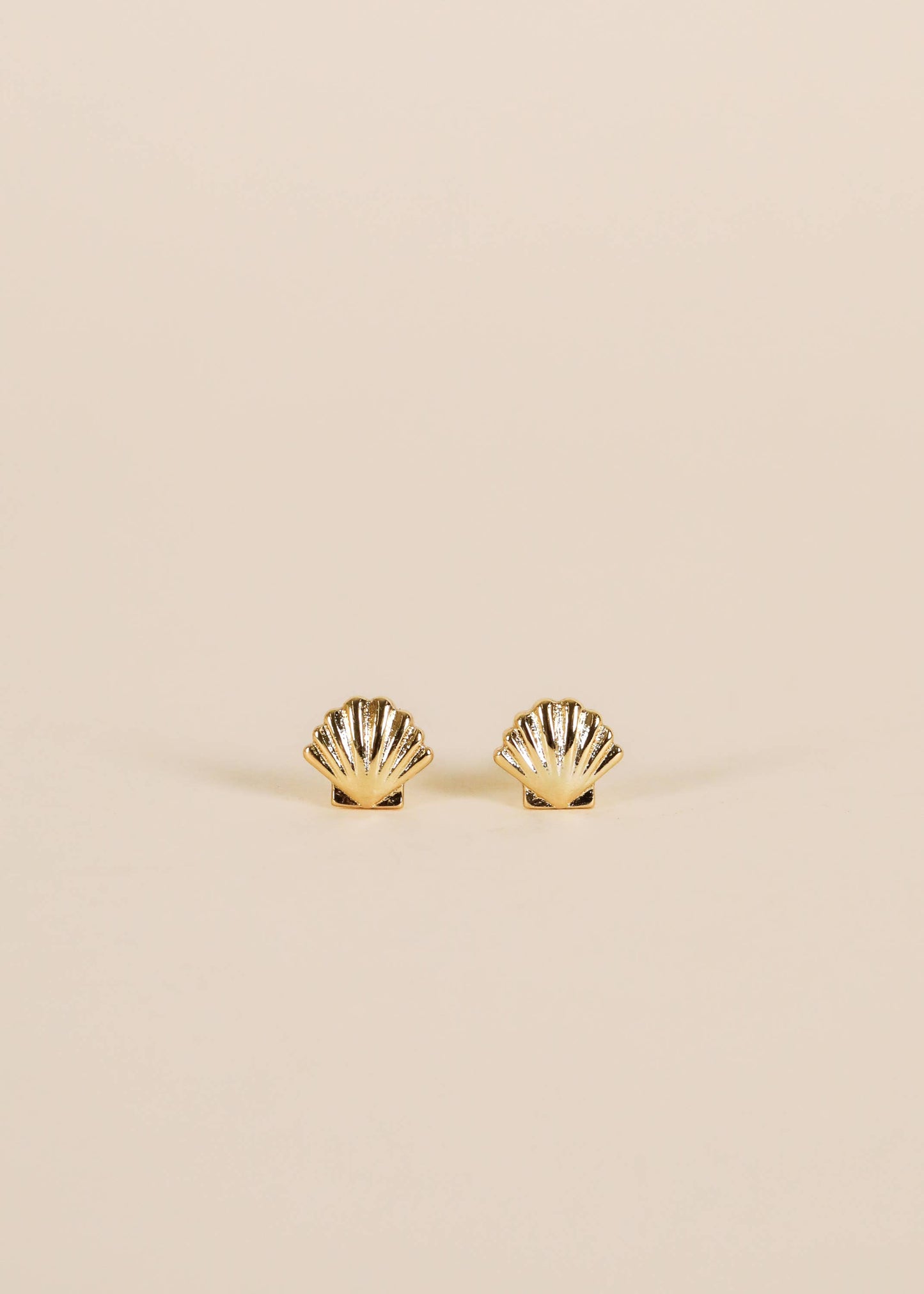 Gold earrings featuring seashell designs by Jax Kelley, showcasing intricate detailing on a white background.