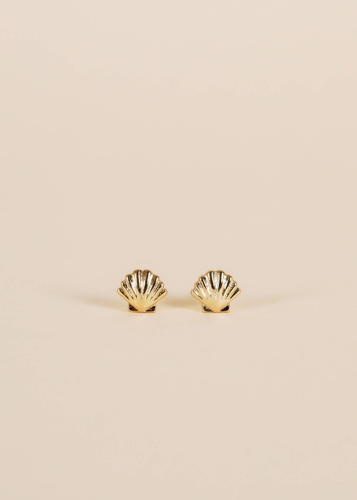 Gold earrings featuring seashell designs by Jax Kelley, showcasing intricate detailing on a white background.