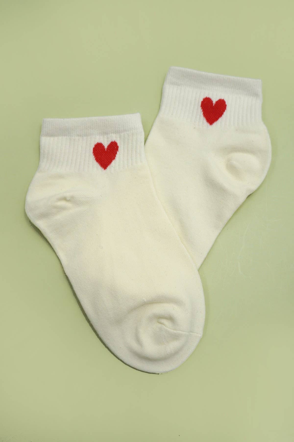 Woman wearing white cotton socks with red heart patterns, from JOSSLYN by Wall to Wall, featuring a cozy, casual style.