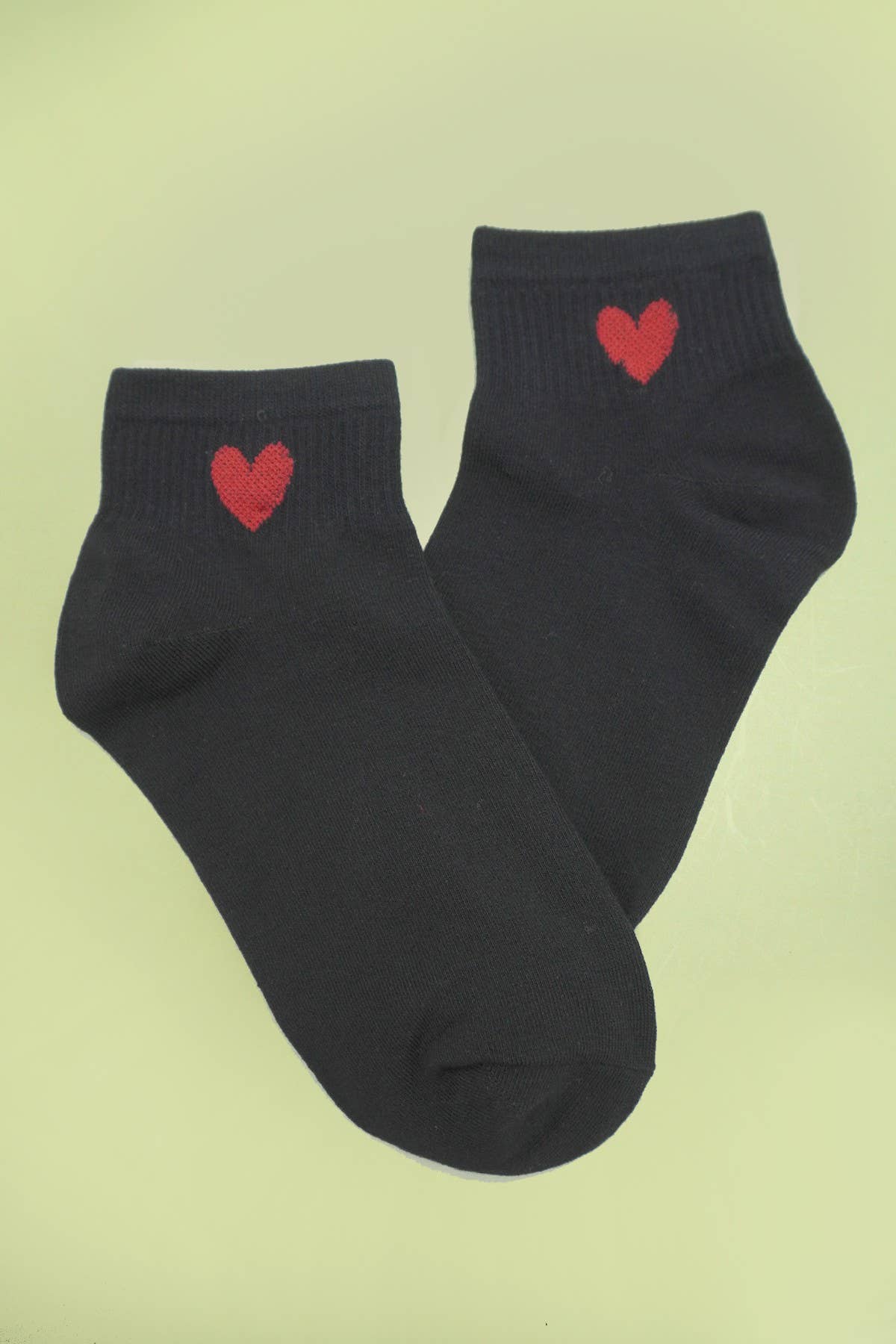 Woman wearing JOSSLYN heart cotton socks featuring red heart patterns on soft white fabric.