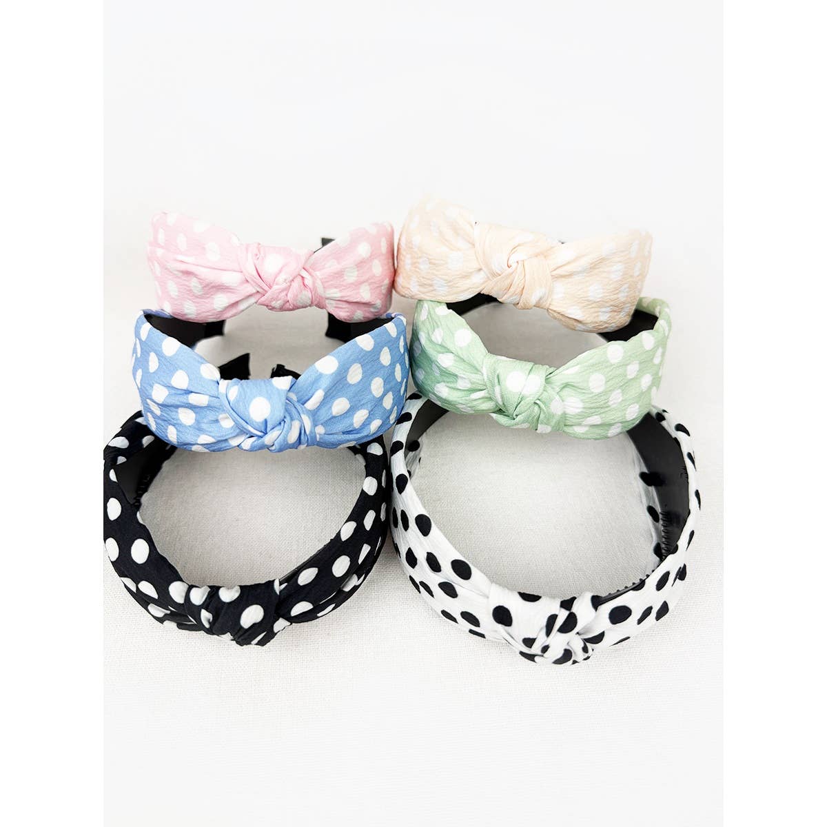 Polkadot print knot hairband by Love and Repeat featuring black and white polka dots and a twisted knot design.