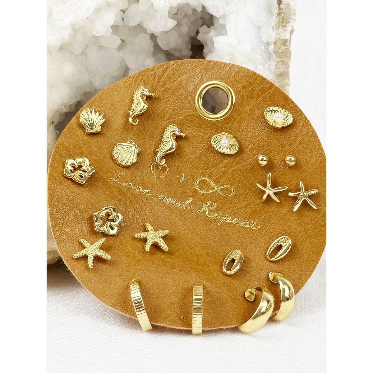 Beach-themed earrings by Love and Repeat featuring colorful, seashell and starfish designs on fishhook findings.