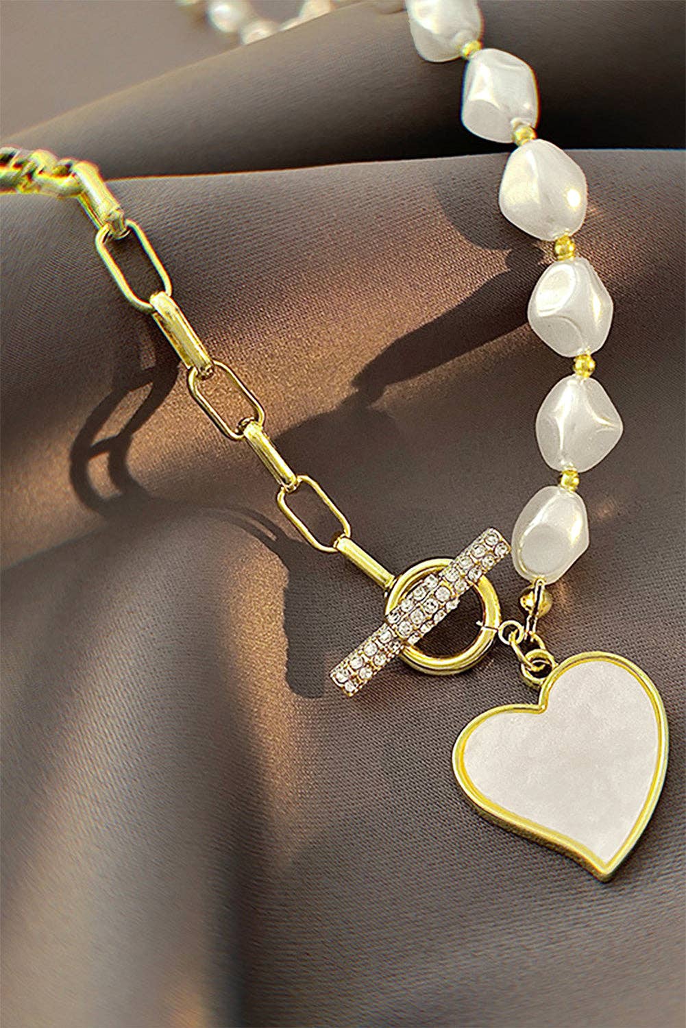 Gold heart-shaped pendant necklace with rhinestone accents and pearl chain, featuring a Lovesoft jewelry design.