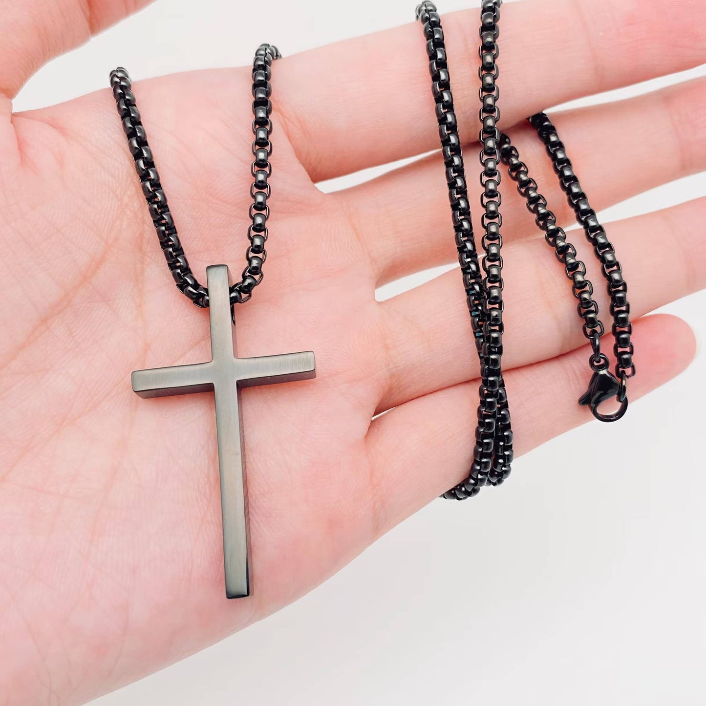 Glossy black stainless steel cross pendant necklace by Mio Queena, featuring a sleek and shiny design.
