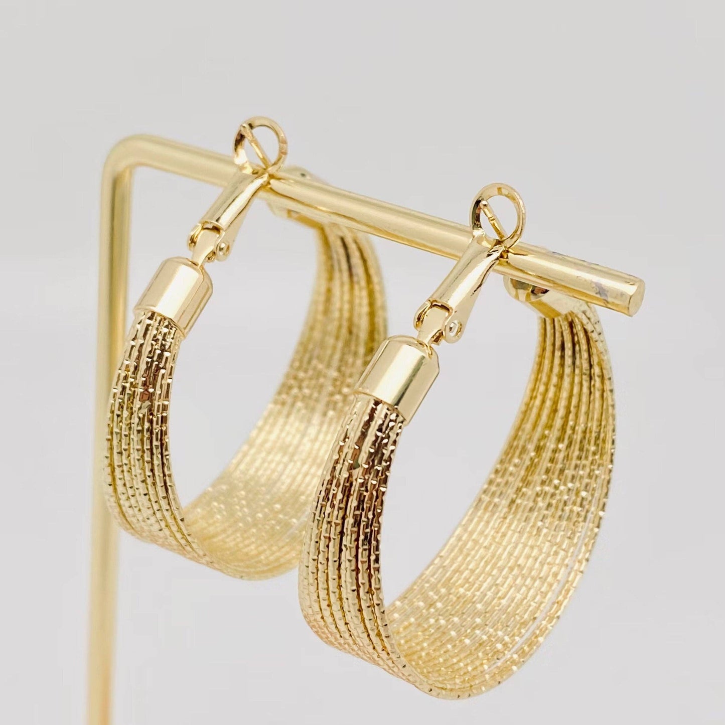 Golden multi-layer coil hoop earring from Mio Queena featuring layered gold coils and a stylish hoop design.