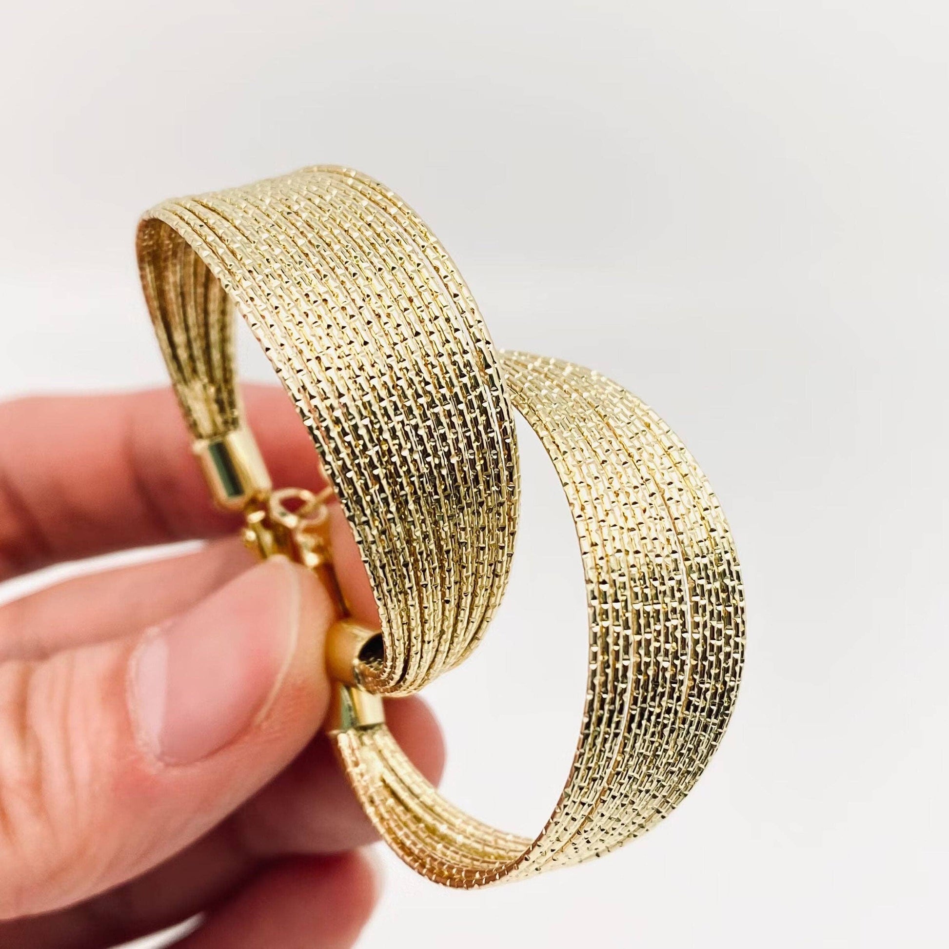 Golden multi-layer coil hoop earring by Mio Queena featuring layered metal coils and a stylish hoop design.