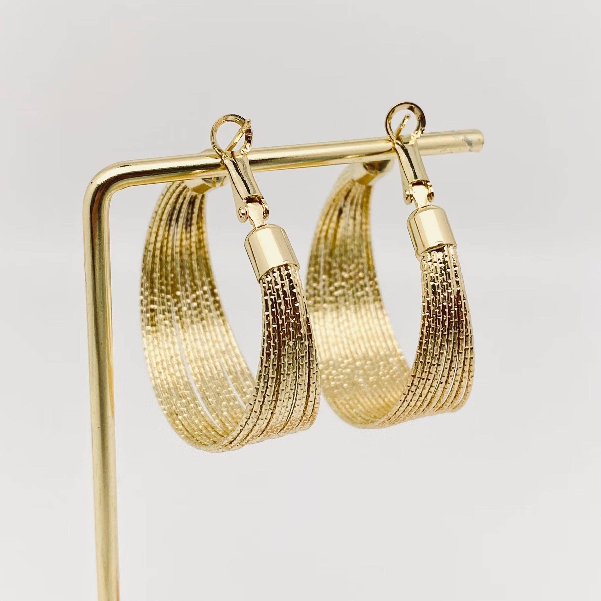Golden multi-layer coil hoop earring by Mio Queena featuring layered coil design and shiny finish.