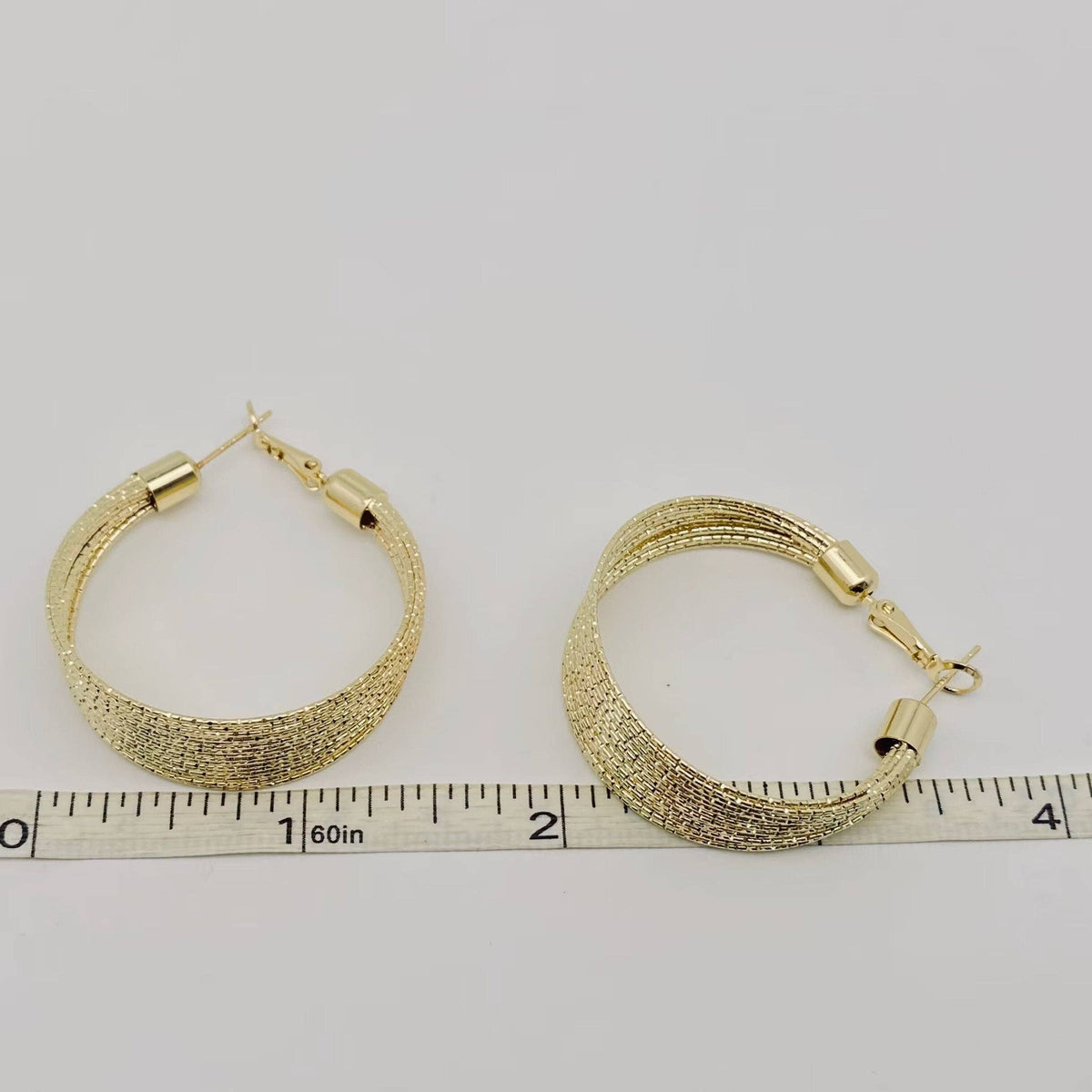 Golden multi-layer coil hoop earring by Mio Queena, featuring layered spiral design and shiny gold finish on a white background.