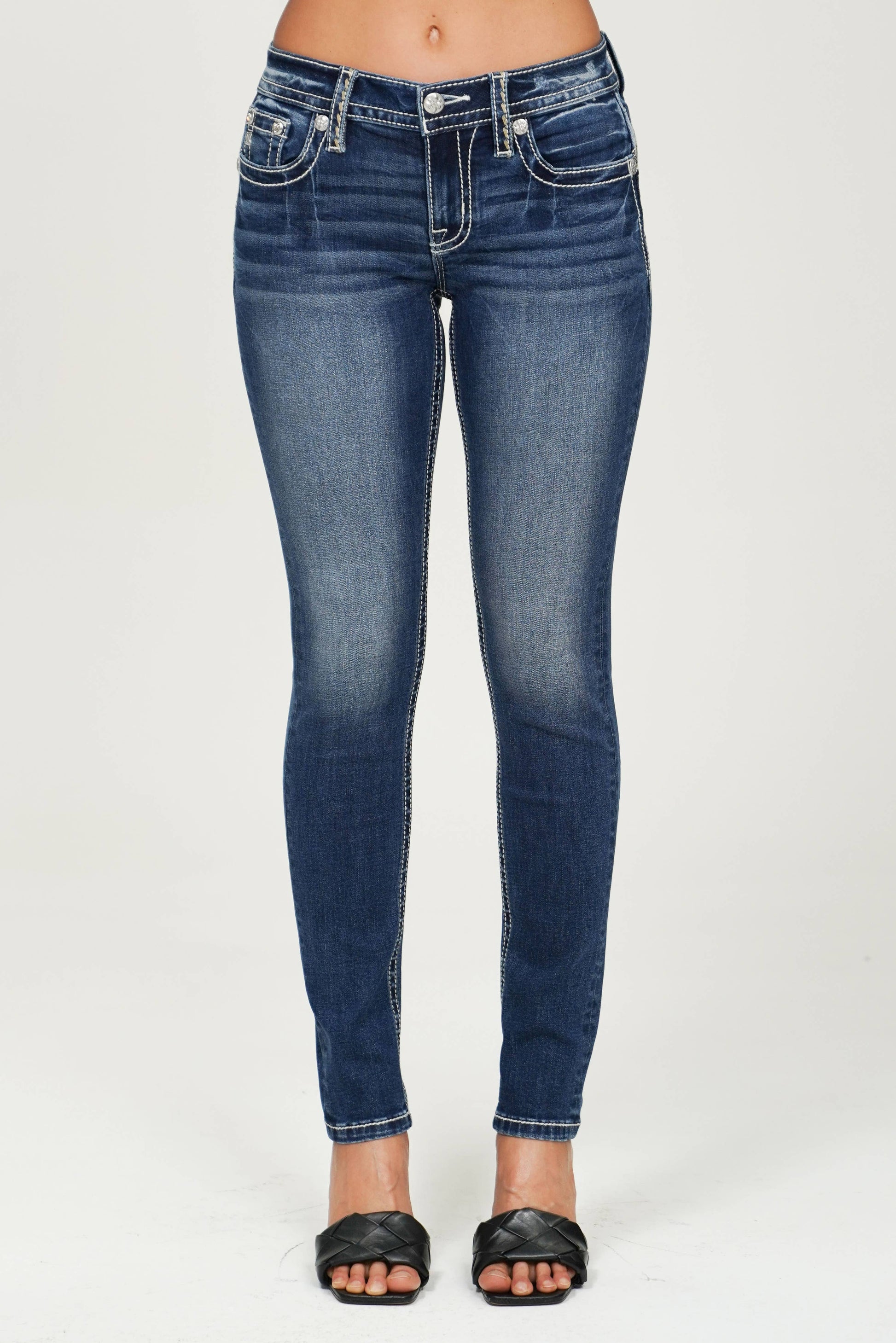 Miss Me mid-rise skinny jeans in dark wash with classic five-pocket style and subtle fading, displayed on a hanger.