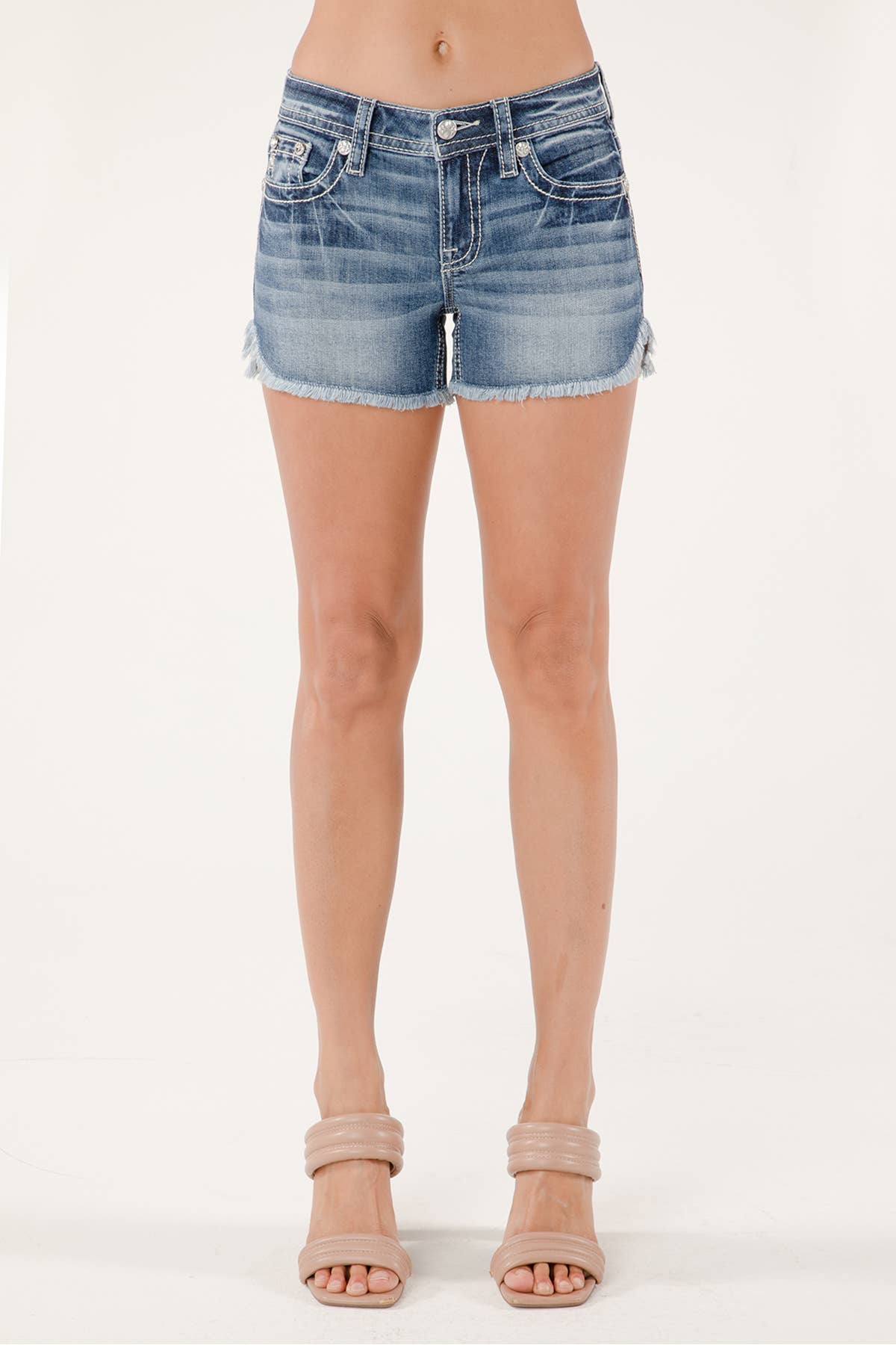 Miss Me mid-rise denim shorts with distressed details and frayed hem, shown on a model against a neutral background.