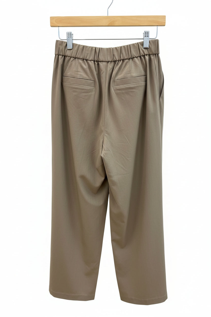 Taupe pants hanging on a hanger with white background