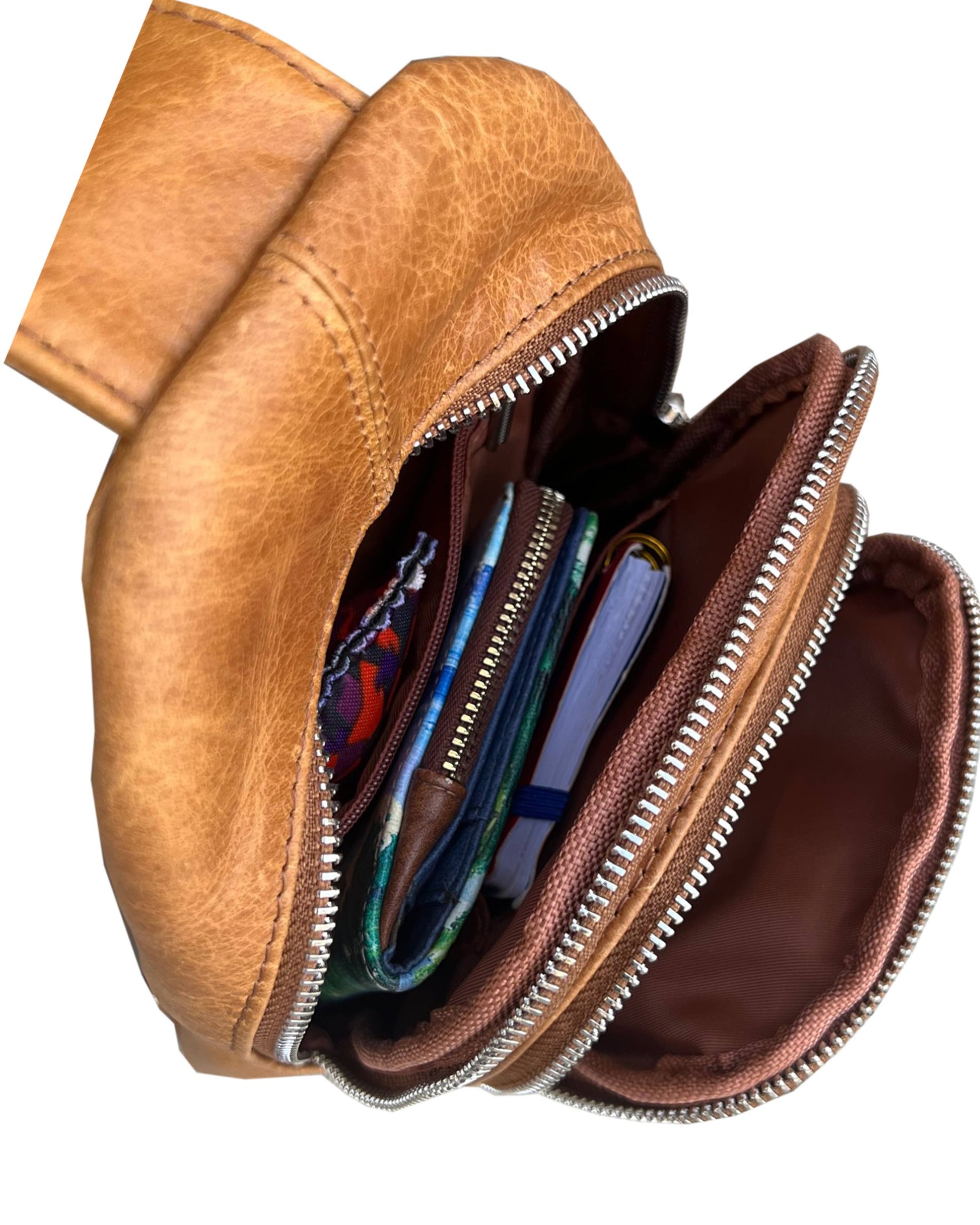 Cowhide leather sling bag with adjustable shoulder strap from Roma Leathers, Inc., featuring a sleek, compact design and natural leather texture.