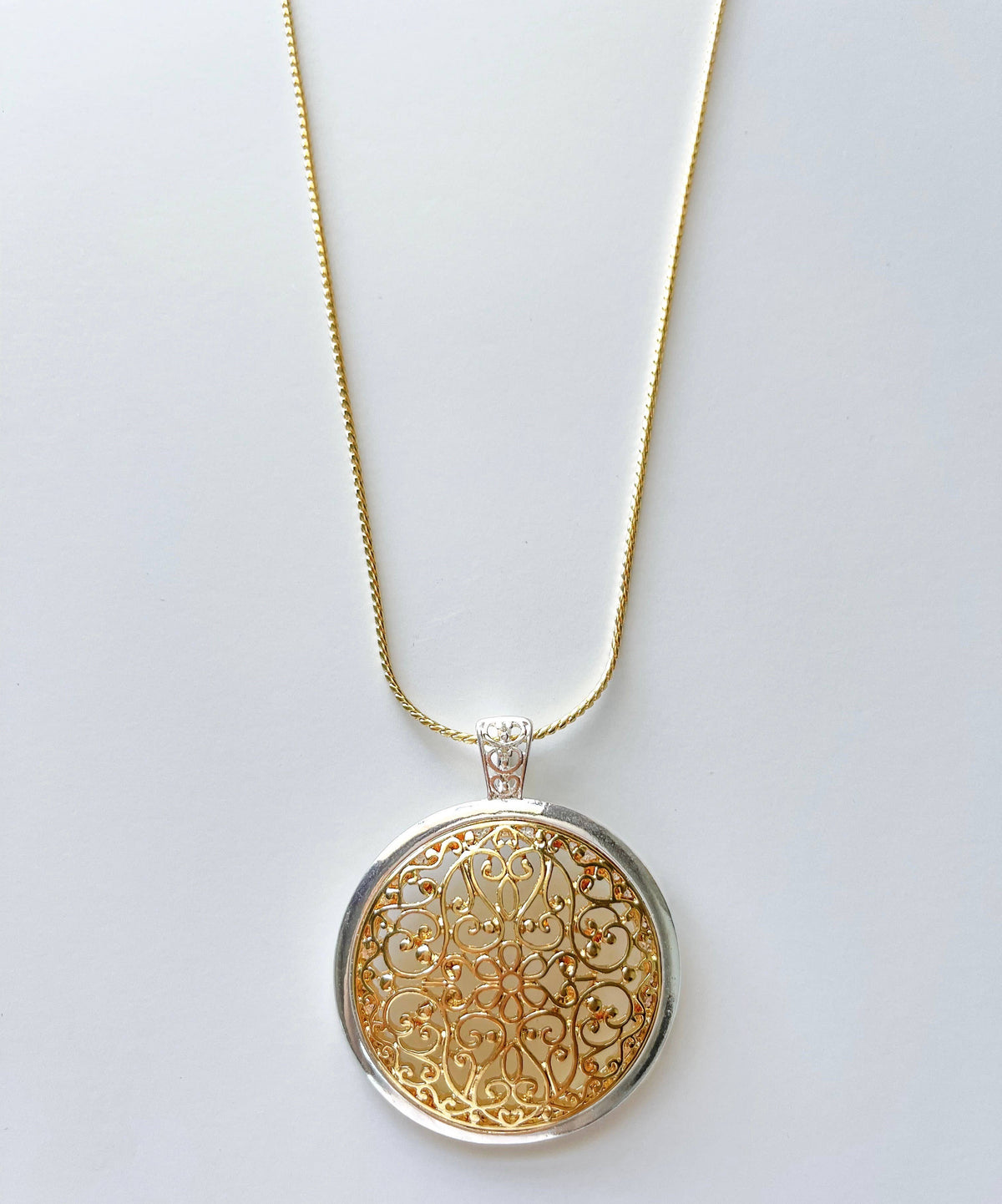 Two-toned domed filigree pendant on a long chain necklace by S & A Fashions, featuring intricate metalwork and elegant design.